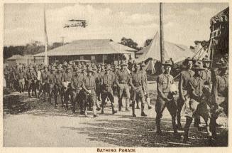 Sepia toned picture of a group of airmen marching through a military camp.