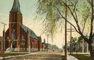 Street scene showing large church on left and houses and trees on right. 