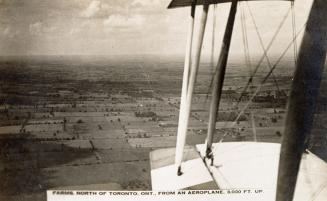 Black and white shot of an air plane flying across a field from the perspective of the wings.