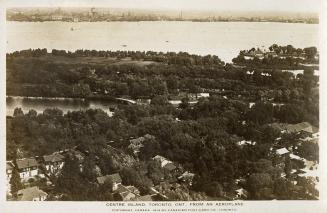 Aerial shot of houses on land beside a lake. B & W.