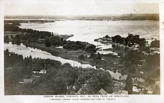 Aerial shot of houses and structures on land beside a lake.