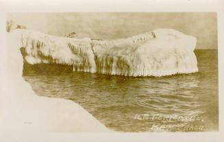 Black and white picture of an ice covered piece of land jutting out into open water.