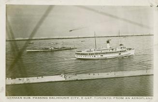 Black and white photograph of a submarine passing a passenger boat on a body of water.