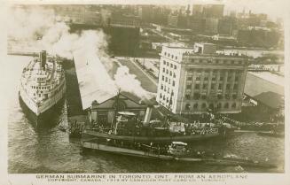 Black and white photograph of a submarine at dockside in a harbor.