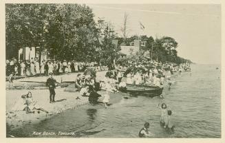 Black and white picture of a crowded beach beside a body of water.