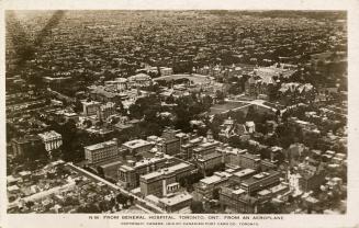 Aerial shot of a large city with tall buildings and a hospital complex in the centre. Black and…