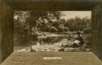 Sepia-toned photograph in a wooden frame of an artist sitting on a stool by a river painting th…