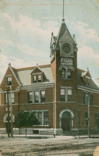 Colorized photograph a a three story public building with a tower on it's corner.