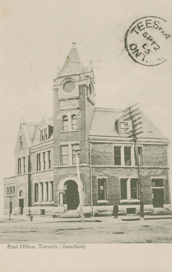 Black and white photograph a a three story public building with a tower on it's corner.