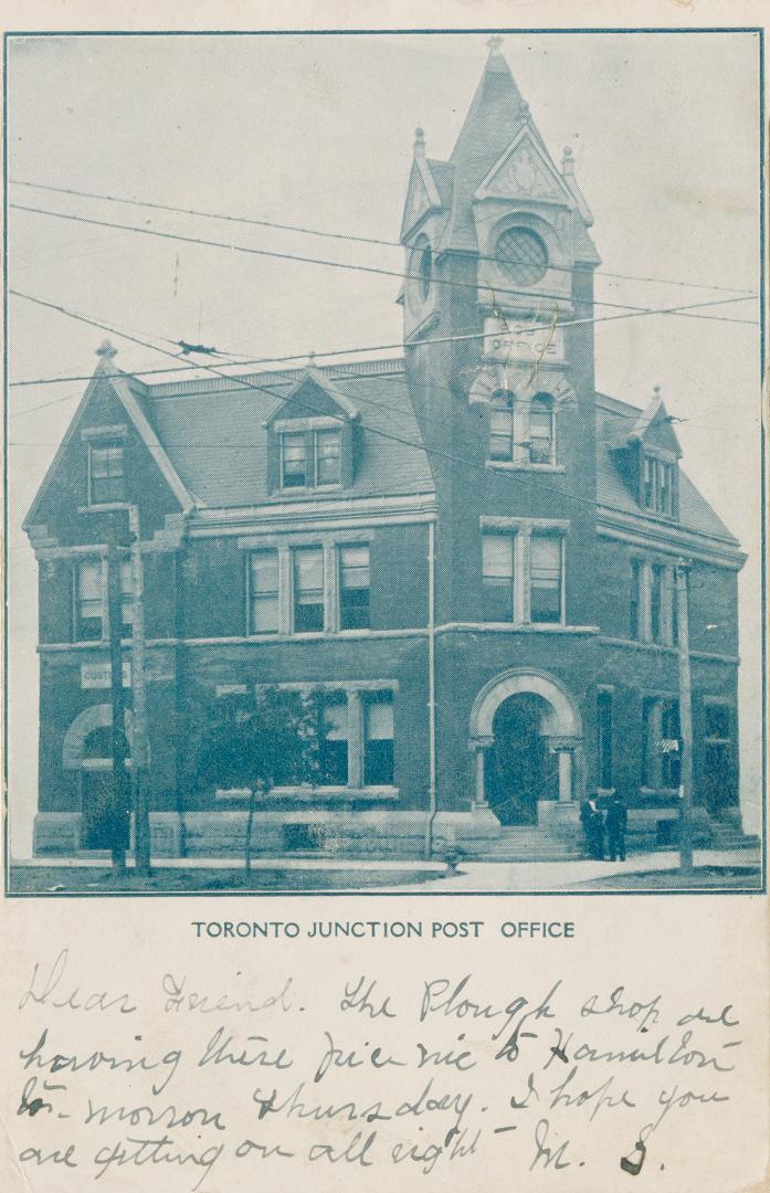 Black and white photograph a a three story public building with a tower on it's corner.