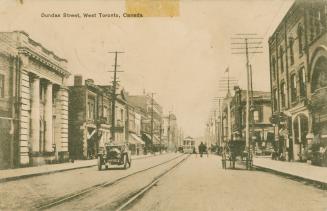 Sepia toned photograph a busy city street with three story buildings on wither side.