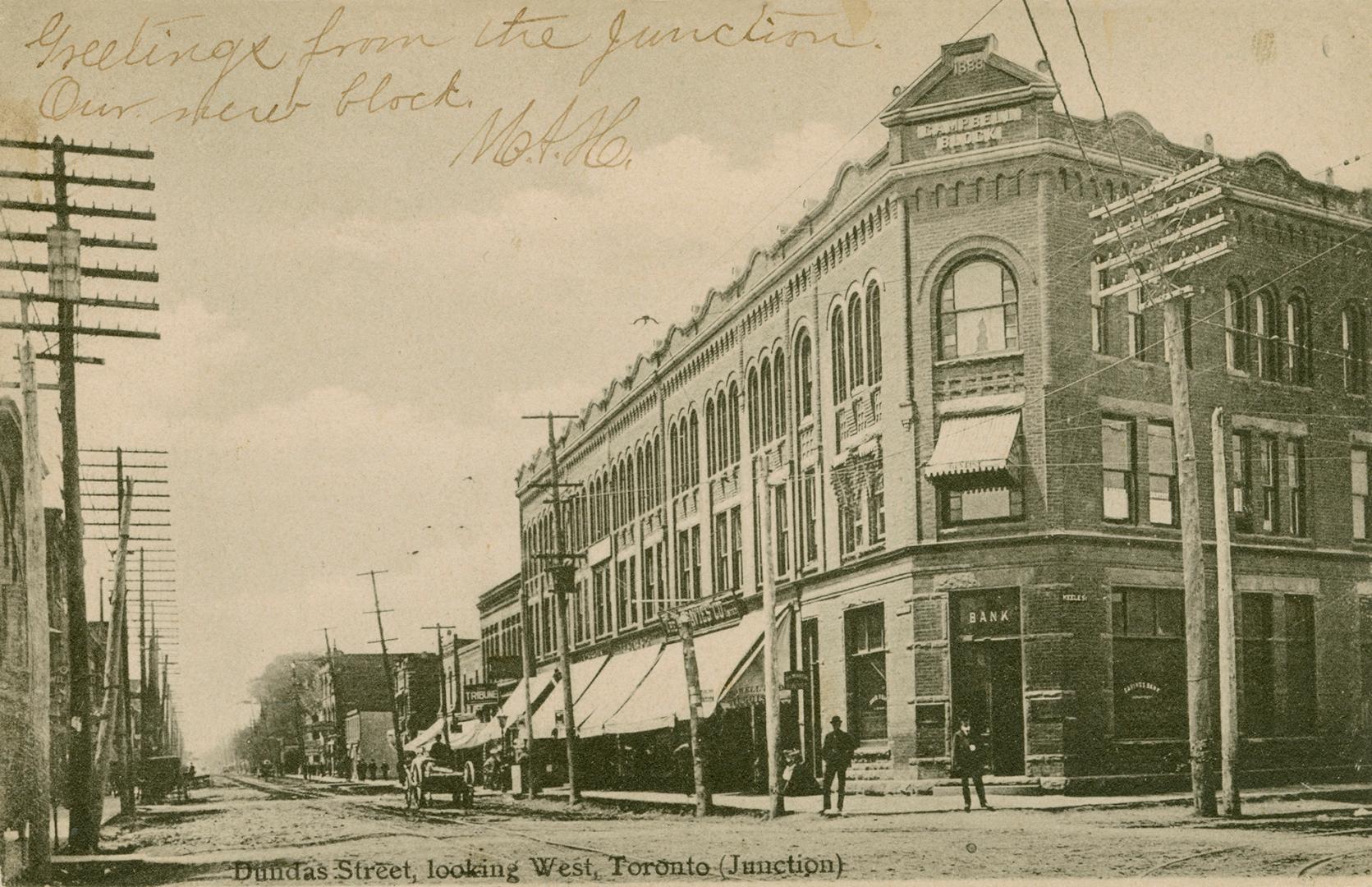 Black and white photograph a busy city street with three story buildings on either side.