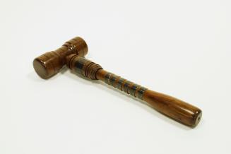 A smooth polished wooden gavel, reinforced by metal bands on the handle.