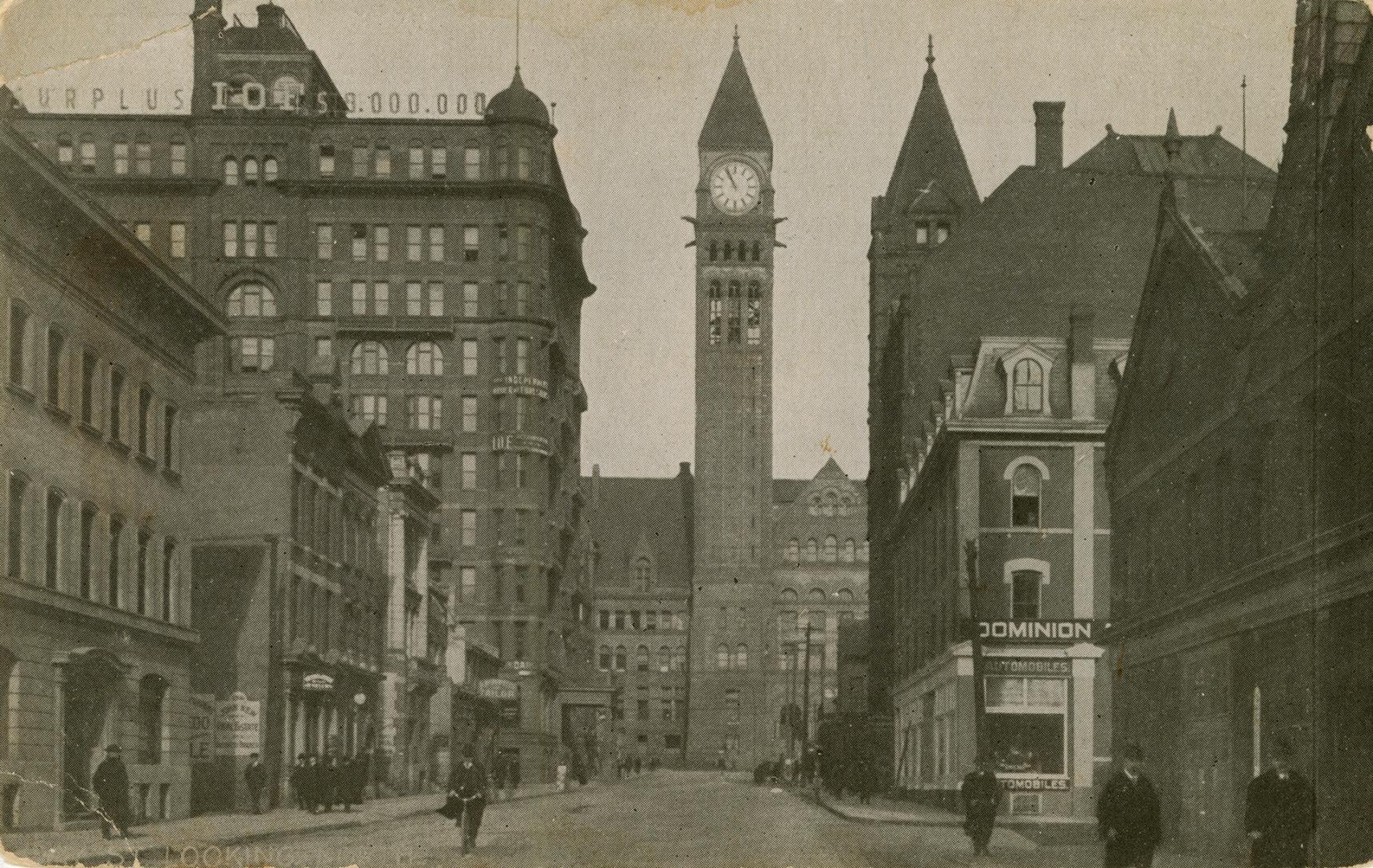 Black and white photograph of a Richardsonian Romanesque building with a clock tower at the end…