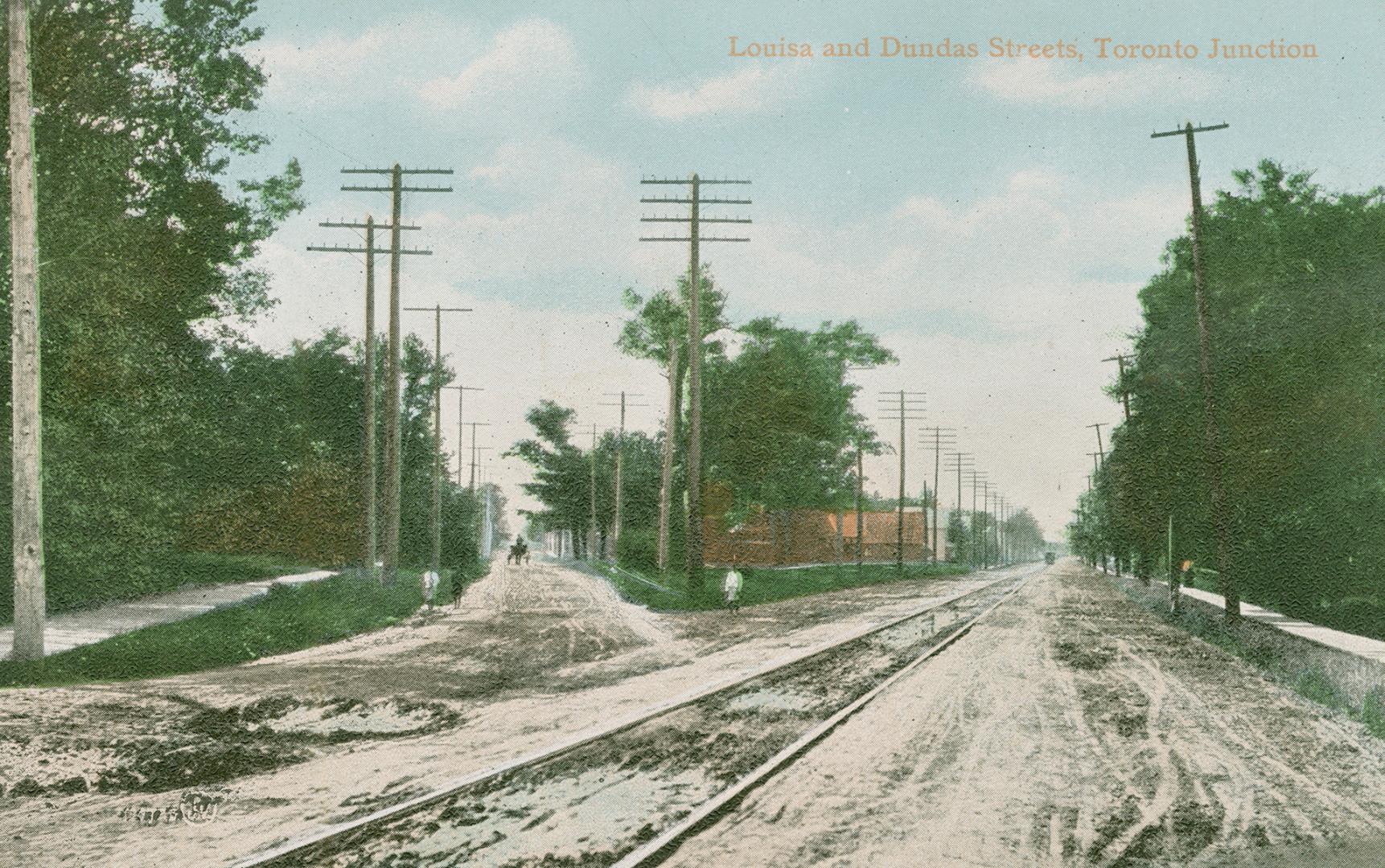 Picture junction of two dirt streets with streetcar tracks on one. 