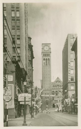 Black and white photograph of a large Ricardsonian Romanesque building with a central clock tow…