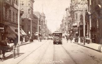 Black and white photograph of a busy city street with tall building on both sides.