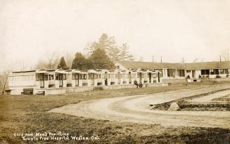 Black and white photograph of a a row of streetcars repurposed into hospital wards. Behind is a…