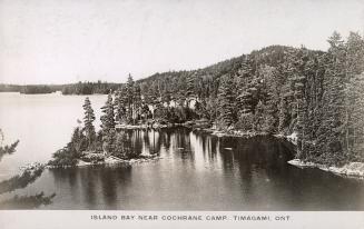 Black and white photograph of a lake in a wild, wooded area.