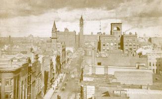 Black and white photograph of a large Ricardsonian Romanesque building with a central clock tow…