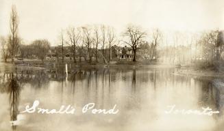 Black and white photograph of a pond with houses on the shoreline.