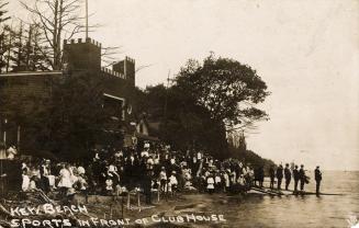 Black and white photograph picture of a beach with crowd watching the water. 