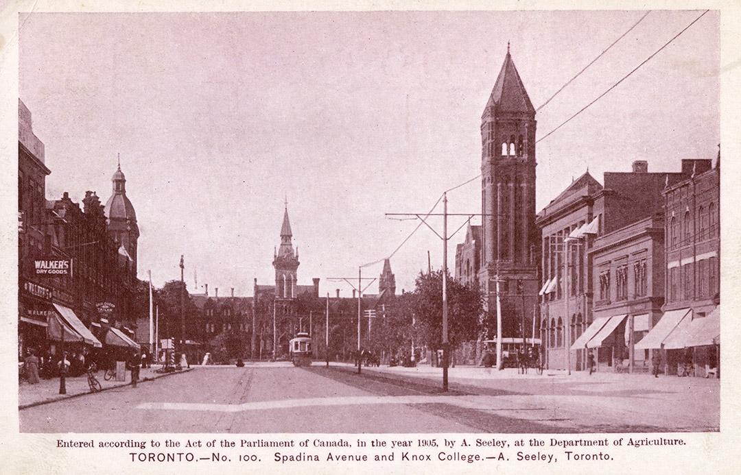 Black and white photograph of a city street scene with a gothic style building at the end of it…