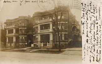 Black and white picture of two, three story apartment buildings.