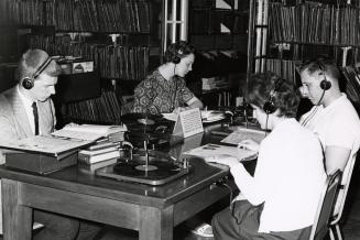 Four people at a table listening to music. 