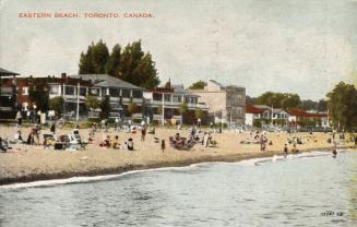 Picture people on a beach with houses in the background. 