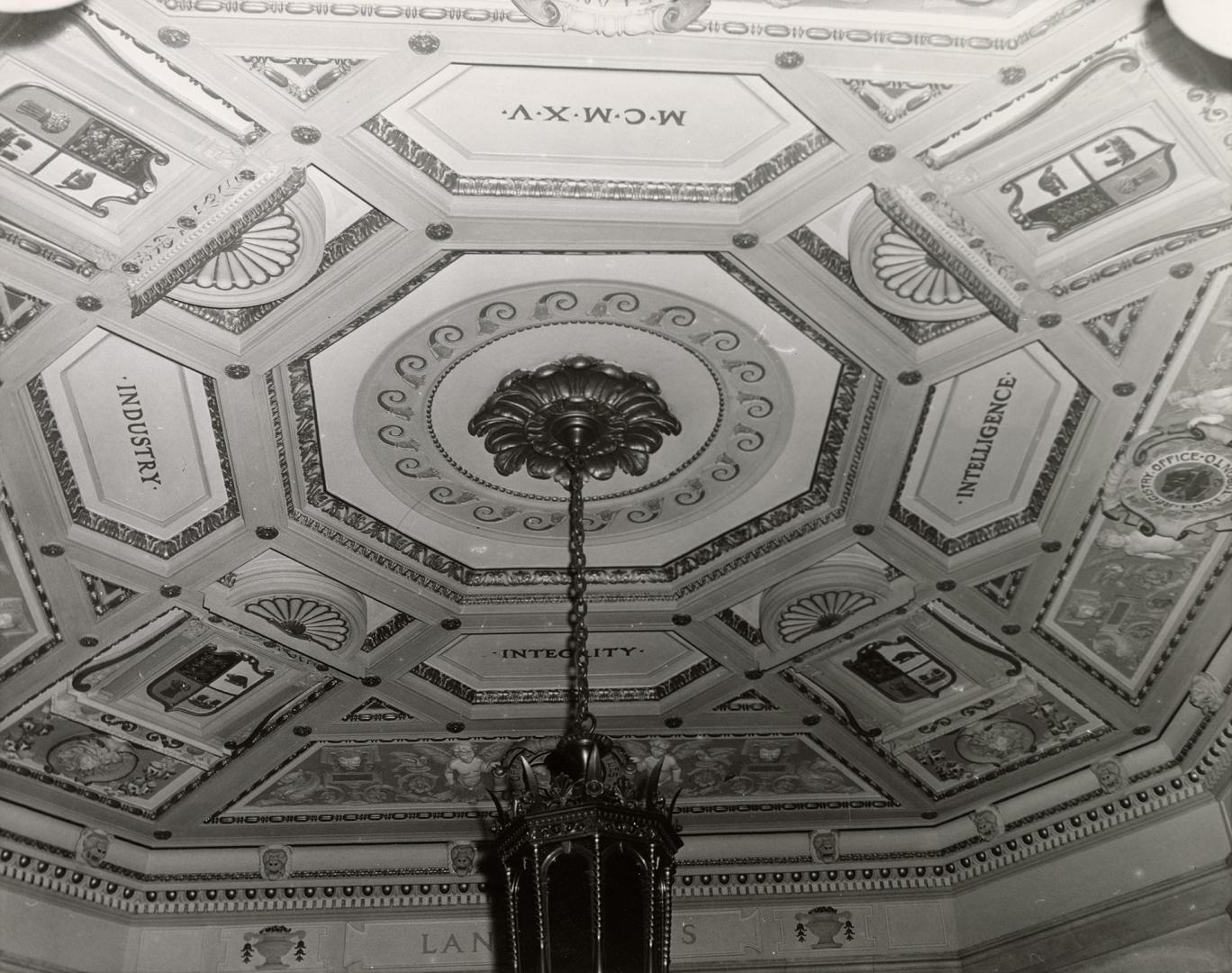 A photograph of a chandelier and the ceiling it is hanging from. The ceiling has an octagon-sha…