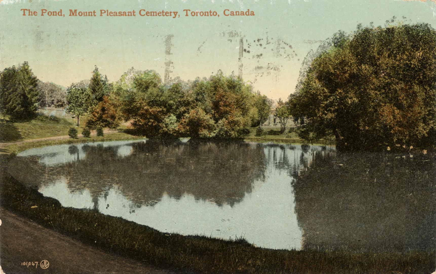 Colour postcard of a pond surrounded by trees. The caption on the top front states, "The Pond, …