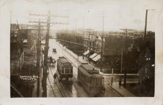 Black and white postcard of Dundas St. E with two streetcars and tracks. The back is filled wit…