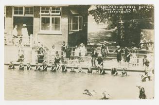 Black and white photograph of people swimming in a large pool.