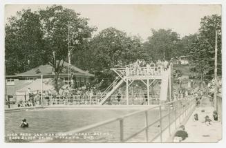 Black and white photograph of people swimming in a large pool.