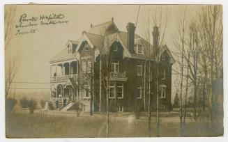 Black and white photograph of large, three story Victorian house.