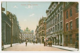 Colorized photograph of city street with tall building on either side. Large, Second Empire sty…