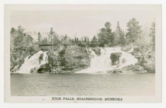 Black and white photograph of waterfalls running into a lake.