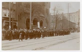 Picture of a military band forming up on street in front of church. 