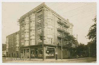 Picture of a five storey apartment building on a street corner. 