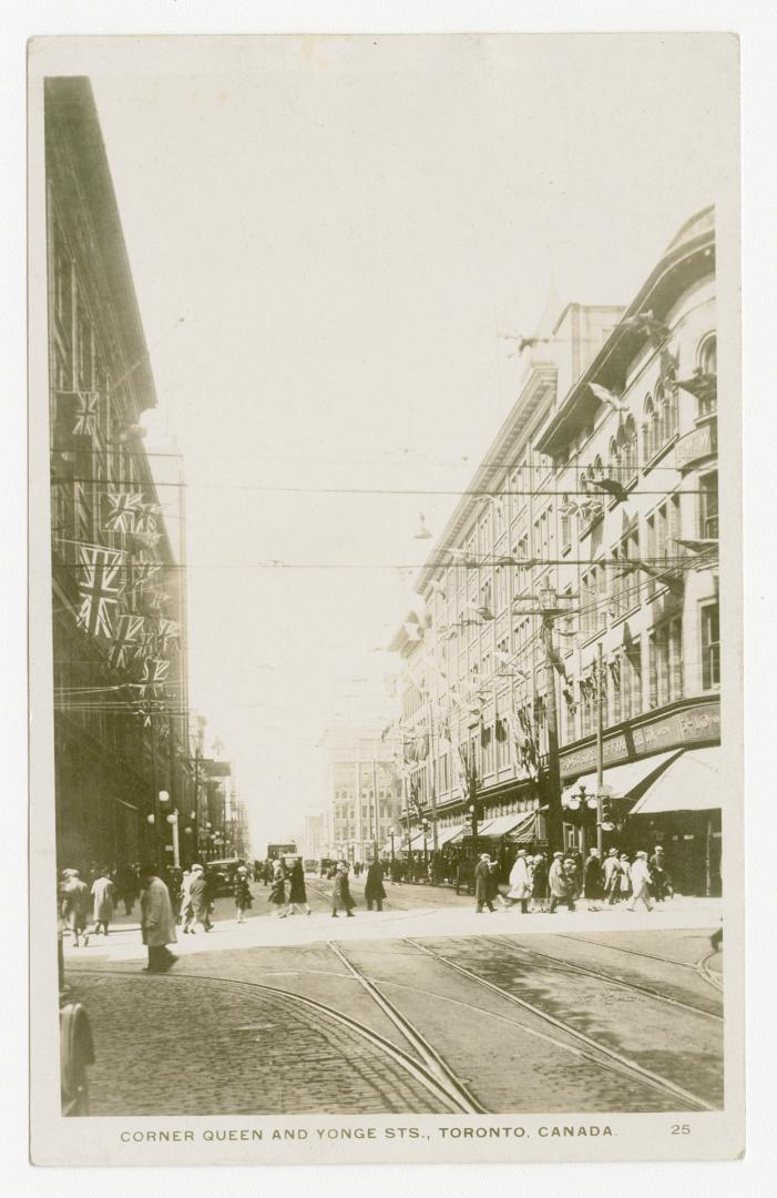 Picture of a street intersection with stores and people walking on the streets. 