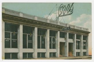 Picture of a cafe with sign on top of building. 