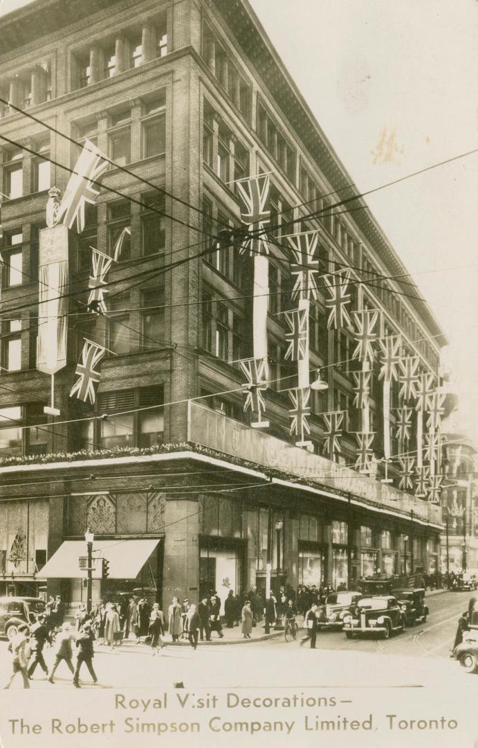 B/W postcard depicting a photo of Simpsons Department Store decorated with British flags with c…