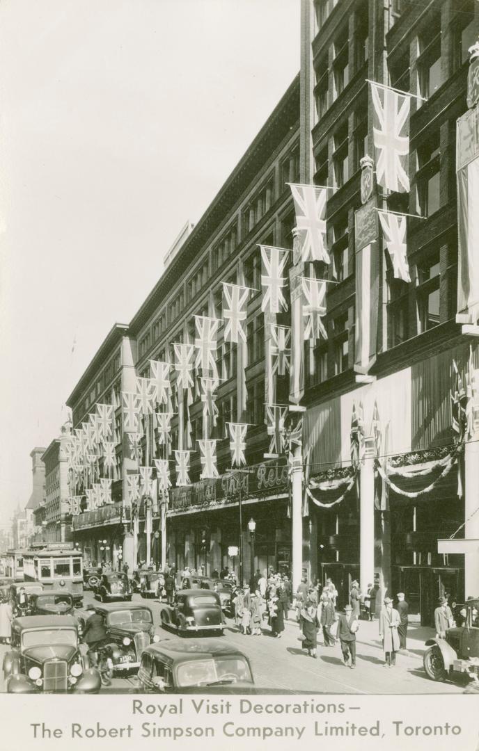 B/W postcard depicting a photo of Simpsons Department Store decorated with British flags with c…