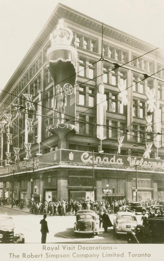 B/W postcard depicting a photo of Simpsons Department Store decorated with British flags with c…