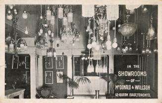 B/W postcard depicting a photo of lighting for sale inside McDonald & Willson's lighting store,…