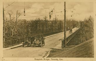 Sepia-toned postcard depicting a photo of the Rosedale Bridge with cars filled with passengers …