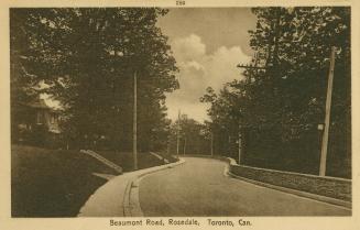 Sepia-toned postcard depicting a curvy road with trees and a house partially visible on the lef…