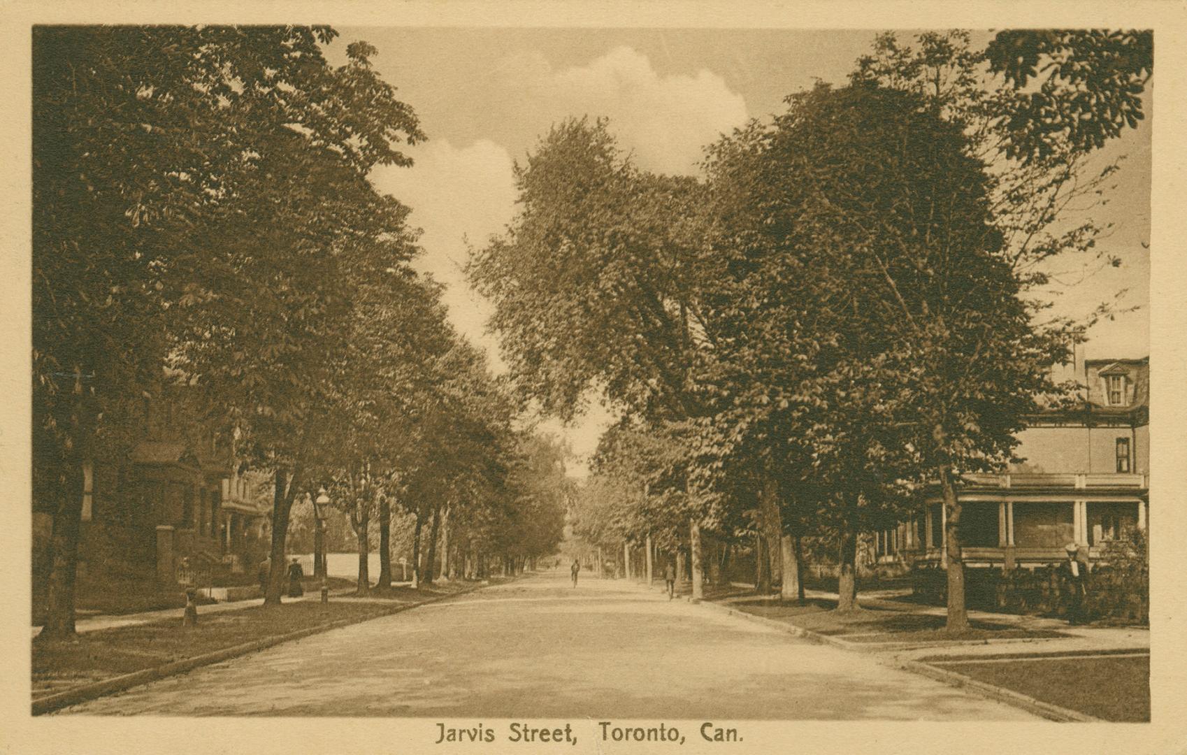 Black and white photograph of a city street bordered by large houses and trees. Coat of arms in…