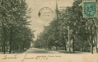 Black and white photograph of a city street bordered by large houses and trees.